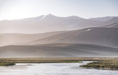 Yüksek dağ manzarası, dağlarda bir nehir bir dağ vadisinde yeşil çayırlar arasında dağların arka planına karşı akar, arka plan için Pamir Dağları 'ndaki manzara