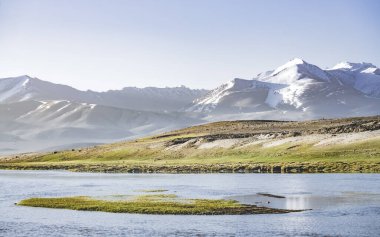 Yüksek dağ manzarası, dağlarda bir nehir bir dağ vadisinde yeşil çayırlar arasında dağların arka planına karşı akar, arka plan için Pamir Dağları 'ndaki manzara