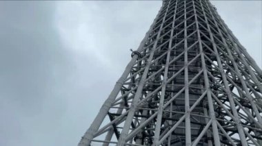 Tokyo Skytree 'nin büyüleyici 4K siyah beyaz videosu, bulutlu bir günde aşağıdan yukarıya bakıyor. İkonik kule bulutlu gökyüzüne karşı dramatik bir siluet yaratıyor. Kentsel, mimari veya seyahat ile ilgili projeler için mükemmel.