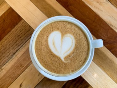 Tahta bir masada bir fincan kahve. Ahşap arka planda bir kupa düz beyaz kahve. Kahve sanatı. Kalp çiçeği şekilli latte sanatı. Uzayı kopyala Yüksek kalite fotoğraf