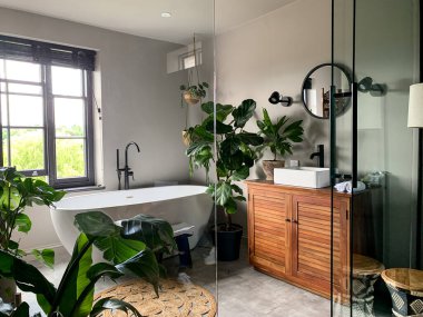 Hoş bir banyo manzarası. Banyo borusu pencerenin yanında. Evde ya da otelde yıkanmak. Endonezya tarzı çok hoş. Banyo manzaralı. Ev Bitkisi odada. Yüksek kalite fotoğraf