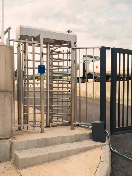 Security access door to a industrial restricted area with an optical reader and a truck on the background with flammable content