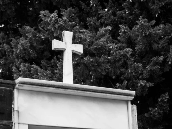 墓碑上的白色石碑十字架的黑白照片 墓碑上的壁龛以树木为背景 — 图库照片