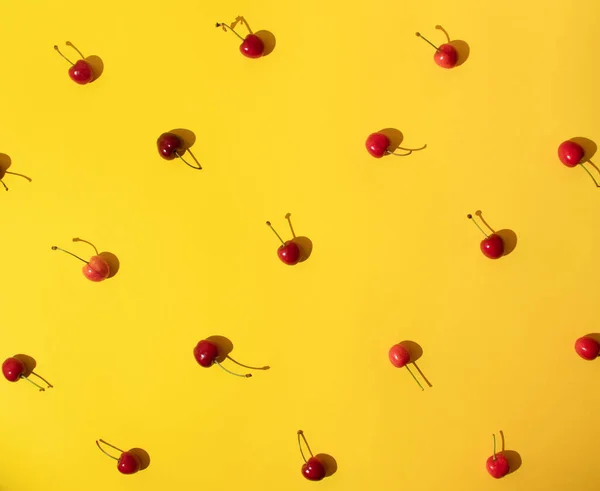 Sarı arka planda parlak kırmızı kirazlı yaz kreatif deseni. Asgari yaz meyvesi fikri.