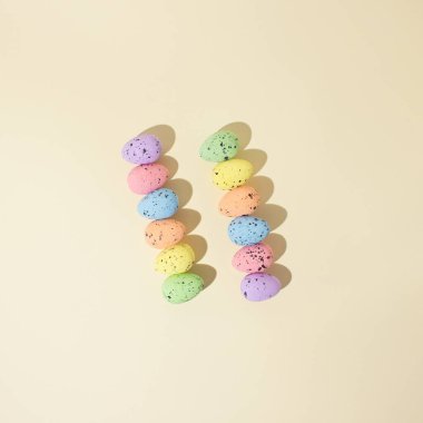 Bej arka planda Pastel Paskalya yumurtaları. Pembe, mor, mavi, turuncu, sarı ve yeşil pastel renkli yumurtalar. Düz konsept.