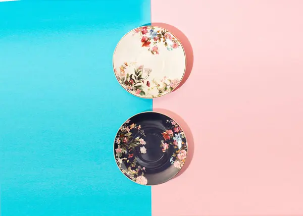 Pembe ve mavi arkaplanda çiçekler olan beyaz ve mavi seramik kupaların bileşimi.