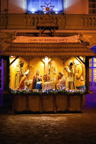 Aydınlatılmış Noel İsa, Meryem, Yusuf, bebek İsa ve Magi 'nin ahşap figürlerinin yer aldığı, şenlikli süslemelerle dolu kırsal bir ahırda geçen Noel sahnesi.