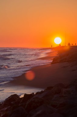 Yalnız çocuk gün batımında sahilde yürüyor.