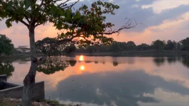 Video gölün kenarında çok güzel bir manzarayla yürüyor ve güneş batmaya hazırlanıyor.