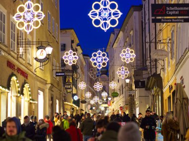 İnsanlar Noel akşamı alışveriş için şehir merkezini ziyaret etmekten keyif alıyorlar. Salzburg şehri Noel ışıklarıyla süslenmiştir.. 