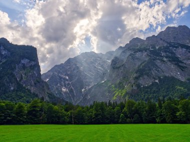 Güneş ışınları, Konigssee Gölü 'nün yakınındaki çayırların ve dağların üzerinden geçiyor. Bavyera, Almanya 