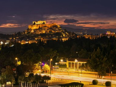Günbatımında Panathenaic Stadyumu 'ndan Akropolis Tepesi manzarası. Sokakta uzun pozlama fotoğrafları ve araba ışığı izleri var. Atina, Yunanistan 