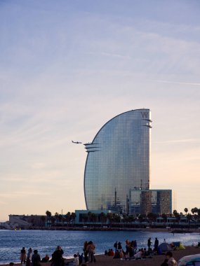 Barselona, İspanya - 20 Kasım 2022 Barcelona Oteli, yaklaşan bir uçakla. Öndeki Barceloneta plajı insanlarla dolu.. 
