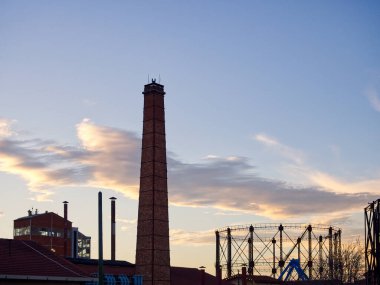Bulutlu karanlık gökyüzüne karşı tuğla baca. Artçı şehir silueti. Technopolis, Atina, Yunanistan