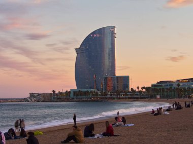 Barselona, İspanya - 29 Şubat 2024: Günbatımı renklerinde yoğun Barceloneta. Arkadaki W Oteli.. 