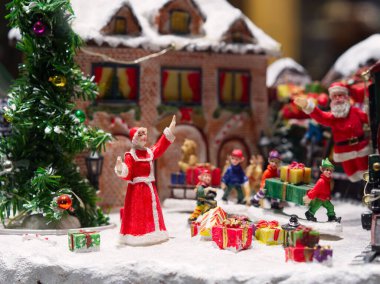 Noel Baba heykelciğinin el salladığı minyatür Noel ağacı sahnesi. Etrafta reklam cinlerini sunar.. 