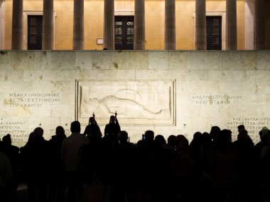 Athens, Greece - December 1, 2024: Shift change at the tomb of the Unknown Soldier in front of the greek parliament at night. People in front.  clipart