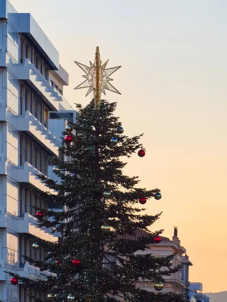 Altın saat günbatımında modern binanın önünde süslenmiş Noel ağacı. Syntagma Meydanı, Atina, Yunanistan
