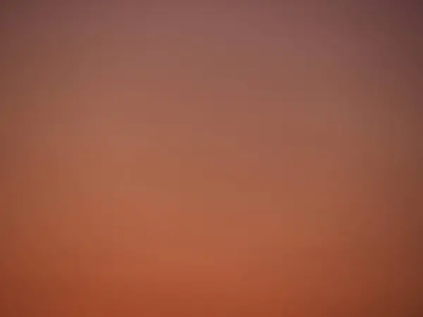 Açık bir alacakaranlık gökyüzünde turuncu rengin yumuşak gradyanı