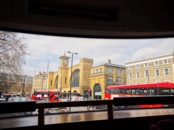 Londra, Birleşik Krallık - 28 Mart 2019: İkonik sarı cepheli ve ön planda kırmızı Londra otobüsleri ile King 's Cross İstasyonu manzarası