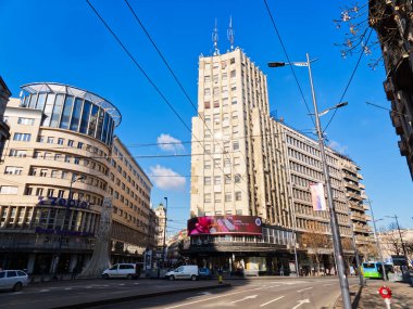 Belgrad, Sırbistan - 11 Ocak 2025: Tramvay hatları ve açık mavi gökyüzü ile kentte yüksek binalar ve sokak manzarası