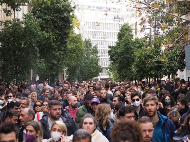 Atina, Yunanistan - 28 Şubat 2025: Çeşitli insanlardan oluşan büyük bir kalabalık, bazıları maske takan ve binaları görünen bir şehir caddesinde toplandı. Tempi tren kazasını protesto etmek