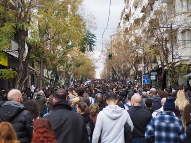 Atina, Yunanistan - 28 Şubat 2025: Atina şehir merkezindeki apartmanlar arasında ağaçlık bir sokak çevresini dolduran büyük bir kalabalık. Tempi tren kazasını protesto etmek