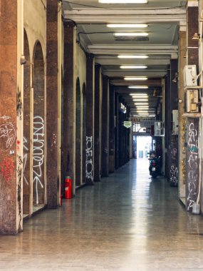 Belgrad, Sırbistan - 11 Ocak 2025: Grafiti kaplı sütunlar, floresan aydınlatma ve uzak çıkışa sahip uzun şehir koridoru