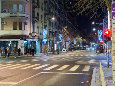 Belgrad, Sırbistan - 10 Ocak 2025: Geceleri mavi tatil süslemeleri, yayalar ve trafik ışıklarıyla kentsel cadde