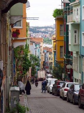 İstanbul 'da renkli binaların, park edilmiş arabaların ve yayaların bulunduğu hareketli dar bir cadde..