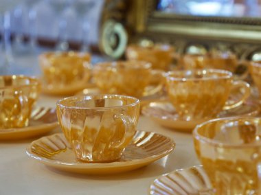 Vintage amber-colored glass teacups and saucers arranged on a table, with a blurred background