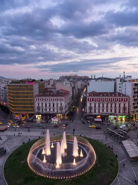 Atina, Yunanistan - 5 Nisan 2025: Atina şehir merkezinin alacakaranlıktaki havadan görünüşü, dairesel aydınlatılmış çeşme ve tarihi binaların yer aldığı