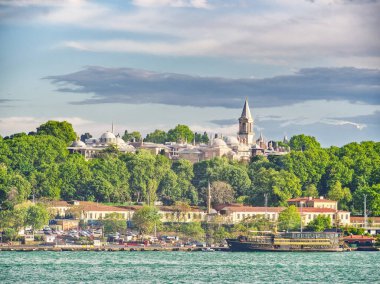 İstanbul manzarası, Topkapı Sarayı, ağaçlar ve Boğaz boyunca uzanan deniz kıyısındaki binalarla iç içe.