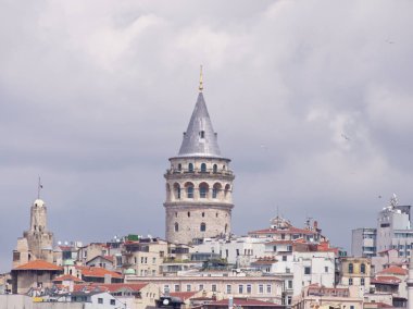 İkonik Galata Kulesi tarihi binalar ve bulutlu gökyüzü ile Istanbuls şehir manzarasının üzerinde yükseliyor