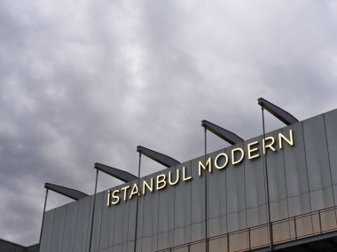 İstanbul, Türkiye - 3 Mayıs 2024: Aydınlatılmış İstanbul Modern Modern Modern Modern Sanat Müzesi tabelası Bulutlu gökyüzü altında kendine özgü aydınlatma donanımlarıyla