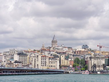 İstanbul, Türkiye - 3 Mayıs 2024: Galata Kulesi, liman bölgesi ve bulutlu gökyüzü İstanbulların tarihi manzarası