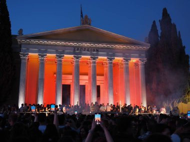 Atina, Yunanistan - 3 Mayıs 2025: Zappeion gece turuncu ışıklarla aydınlatıldı, kalabalık Atina Şehir Festivali 2025 'te bir etkinlik için önünde toplandı