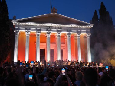 Atina, Yunanistan - 3 Mayıs 2025: Zappeion, Atina Şehir Festivali sırasında büyük bir kalabalık tarafından çevrelenmiş, turuncu ışıkla gece aydınlandı