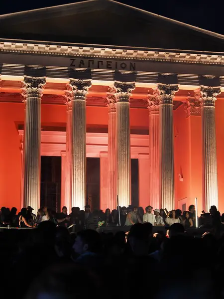 Atina, Yunanistan - 3 Mayıs 2025: Zappeion, 2025 Atina Şehir Festivali sırasında aşağıdaki insanların siluetleriyle akşam gökyüzüne karşı ılık bir ışıkla yıkandı