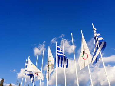 Panathenaic Stadyumu 'ndaki Yunan ve Olimpiyat bayrakları, beyaz bulutlu mavi bir gökyüzü üzerinde dalgalanıyor. Atina, Yunanistan