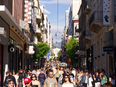 Atina, Yunanistan - 31 Mayıs 2025: Her iki tarafında dükkanlar ve binalar bulunan kalabalık Ermou caddesi, güneş ışığında yürüyen çok sayıda yaya