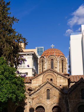 Panaghia Kapnikarea Kilisesi 'nin kubbeli çatısı ve kemerli pencereleri, Ermou Caddesi' nin ortasında modern binalar ve ağaçlarla çevrili. Atina, Yunanistan