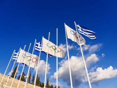 Panathenaic Stadyumu 'ndaki Olimpiyat ve Yunan bayrakları, Yunanistan' daki Olimpiyat Oyunlarını sembolize eden bulutlarla mavi gökyüzünde dalgalanıyor