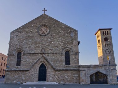 Rodos şehrinde Meryem Ana 'nın duyurusu katedralinin ön cephesinde bir haç ve mavi gökyüzüne karşı ayrı bir çan kulesi var.