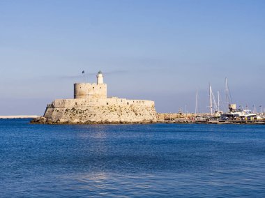 Deniz feneri ve limanın içinde sakin mavi suları olan modern yatları olan Rhodes Adası kalesi. Yunanistan