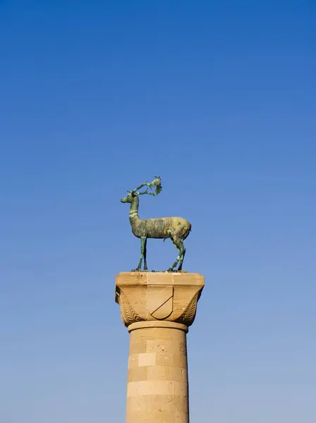 Rhodes Limanı 'ndaki ünlü bronz geyik heykeli, boynuzları açık mavi gökyüzü arka planında uzun bir taş sütunun üzerinde duruyor. Rodos Adası, Yunanistan