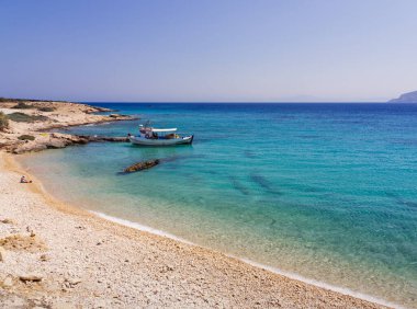 Turkuaz suları ve kıyıya yakın küçük bir balıkçı teknesi olan Yunan adası sahili. Koufonisia Adaları, Kiklad Adaları, Yunanistan