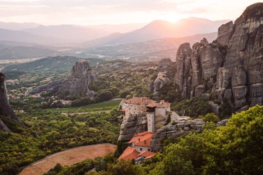 Günbatımında Meteora vadisi ve tarihi kanyonu, Kalambaka, Yunanistan, gölgeler, çarpık yol, köprü ve dağların nefes kesen manzarası.