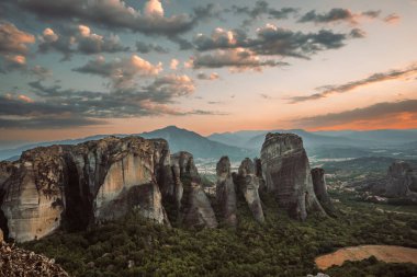 Günbatımında Meteora vadisi ve tarihi kanyonu, Kalambaka, Yunanistan, gölgeler, çarpık yol, köprü ve dağların nefes kesen manzarası.