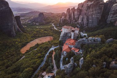 Günbatımında Meteora vadisi ve tarihi kanyonu, Kalambaka, Yunanistan, gölgeler, çarpık yol, köprü ve dağların nefes kesen manzarası.